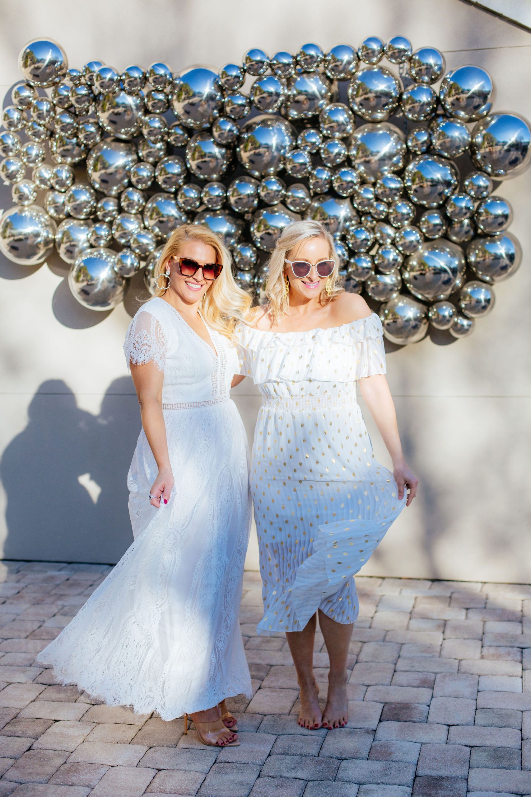 Style Blogger Jenn Truman @jtstjtst11 at the Epicurean Hotel, Autograph Collection poolside and in a bohemian white lace dress with clear heels and sunglasses on. She's also wearing silver bamboo Lisi Lerch earrings