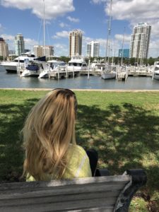 Woman sitting on bench overlooking marina.