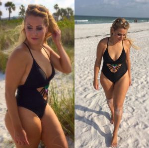 Woman in black swimsuit on sandy beach.