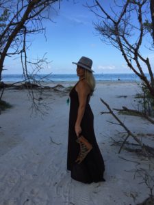 Woman on beach with hat and sandals.