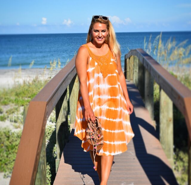 Woman walking on boardwalk by the beach.