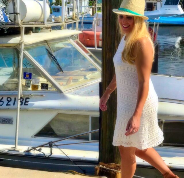 Woman in white dress by a boat.