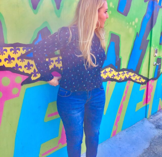 Woman posing against colorful graffiti wall.