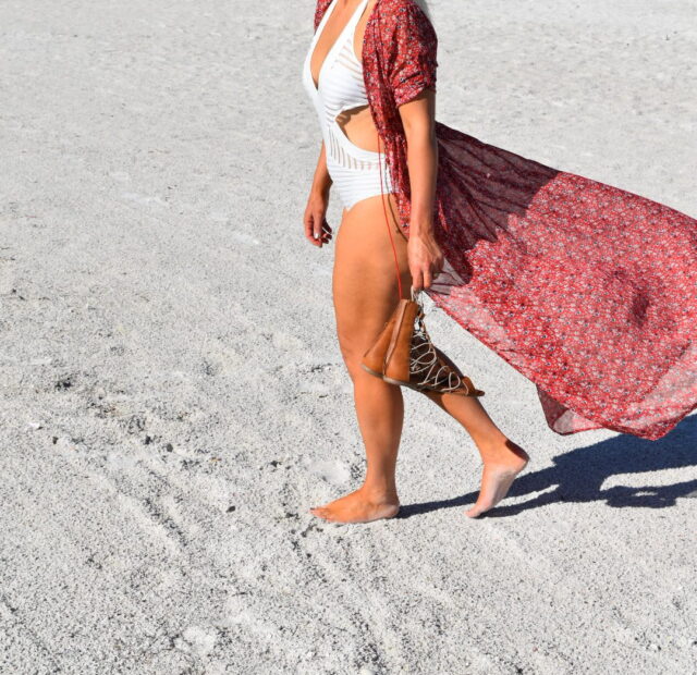 Woman in beach attire walking on sand.