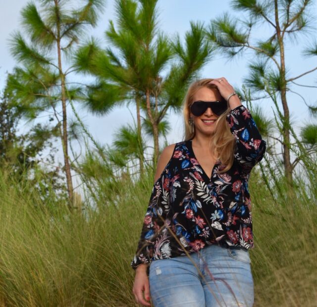 Woman in nature wearing sunglasses and jeans.
